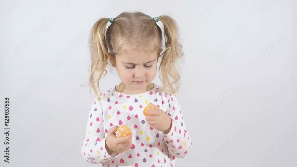Cute little girl eating an orange, close up isolated on a white background. fast motion Cute little girl eating an orange, close up isolated on a white background. fast motion