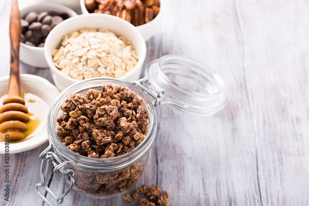 Homemade chocolate granola ingredients, nuts, oats, honey on white wooden background. Healthy brakfast concept with copy space. Homemade chocolate granola ingredients, nuts, oats, honey on white wooden background. Healthy brakfast concept with copy space.