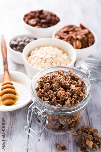 Homemade chocolate granola ingredients, nuts, oats, honey on white wooden background. Healthy brakfast concept.