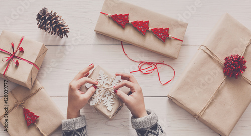 Obraz na plátně Woman's hands wrapping christmas holiday present with craft twine