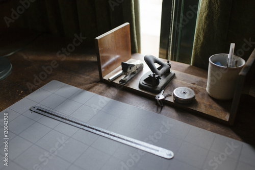 A desk in a study with a ruler, a stapler and a hole puncher. photo