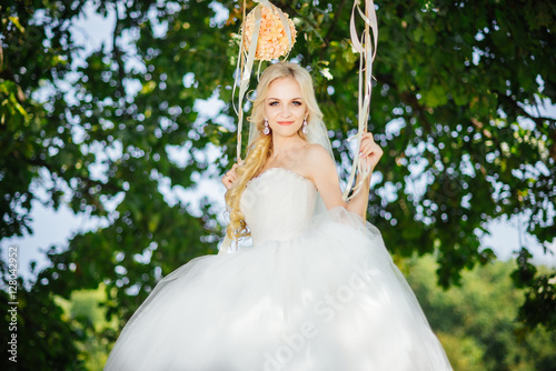Wedding bride. Young happy bride riding on a swing after wedding ceremony. Wedding day.