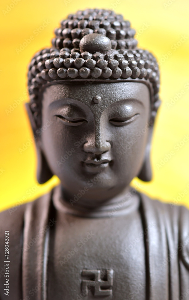 The face of Buddha Zen sculpture on a yellow background