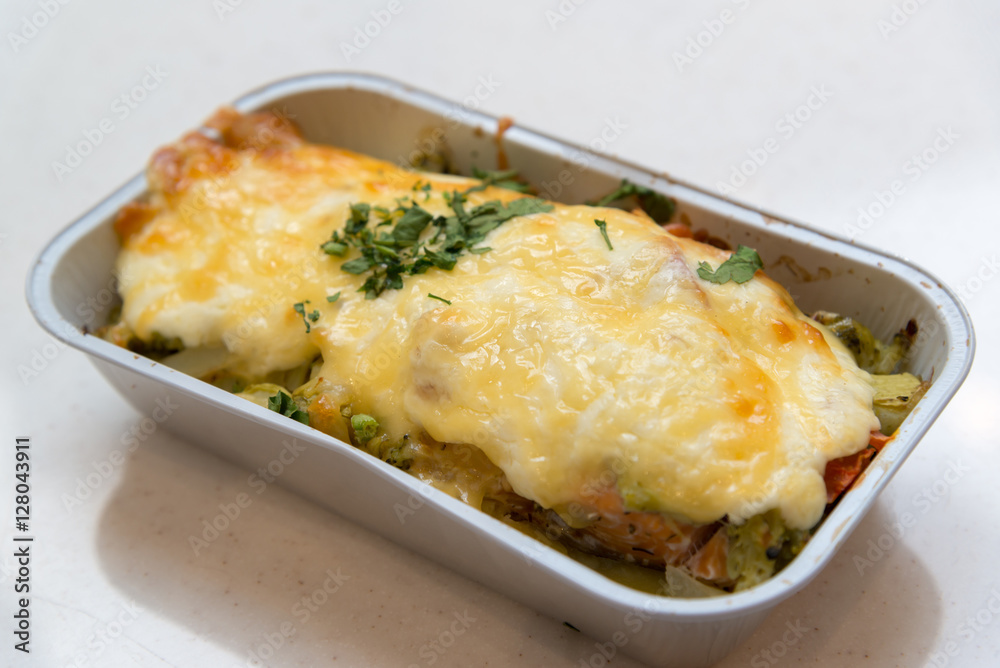 Trout baked with vegetables and cheese in batch trays Trout baked with vegetables and cheese in batch trays