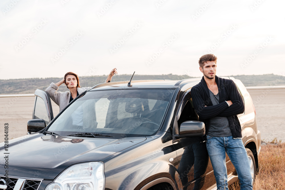 Young couple standing at their car on the seaside