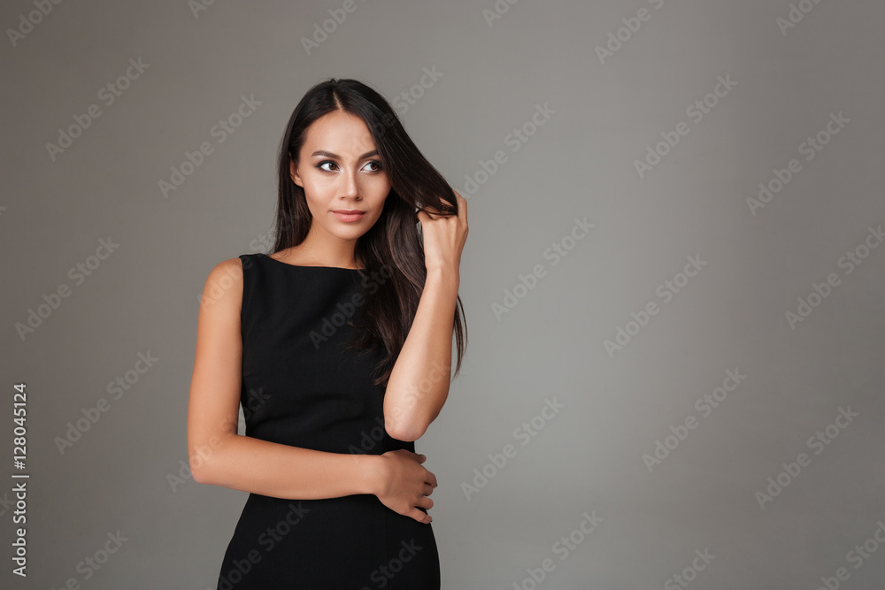 Obraz premium Portrait of smiling beautiful woman in black dress looking away