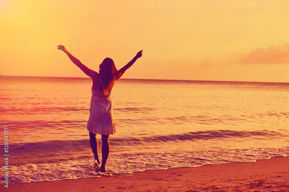 Woman enjoying freedom on a ocean shore with hands raised Woman enjoying freedom on a ocean shore with hands raised