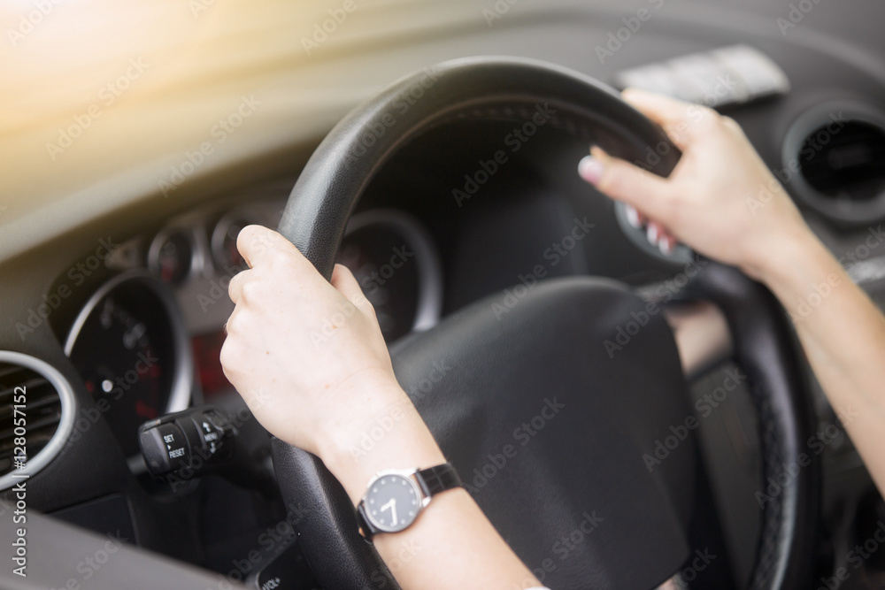 Lifestyle portrait of an attractive smiling woman driving a car, confident driver. Young beautiful lady with fastened safety seatbelt driving silver modern car. Girl on car trip, looking at camera