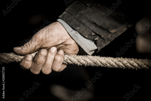 Hand pulling the rope, Grey background