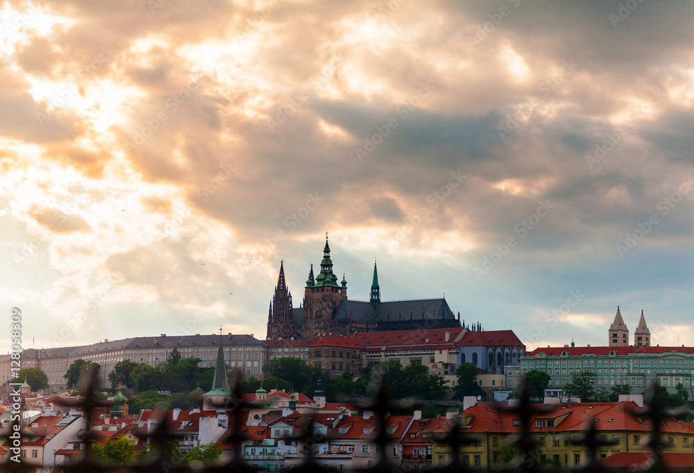 Panoramic view of St. Vitus Cathedral and Castle in Prague, Czech Republic. Beautiful dramatic sunset sky with rays of making their way through clouds.