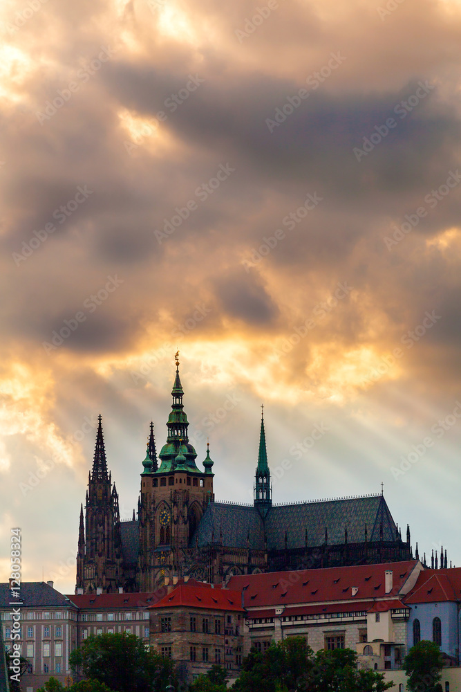 Panoramic view of St. Vitus Cathedral and Castle in Prague, Czech Republic. Beautiful dramatic sunset sky with rays of making their way through clouds.
