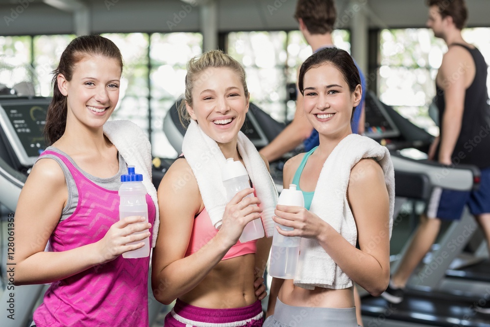 Athletic smiling women posing with bottle of water Athletic smiling women posing with bottle of water