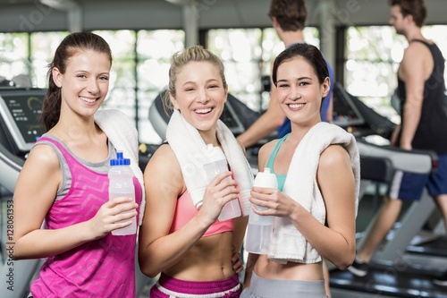 Athletic smiling women posing with bottle of water