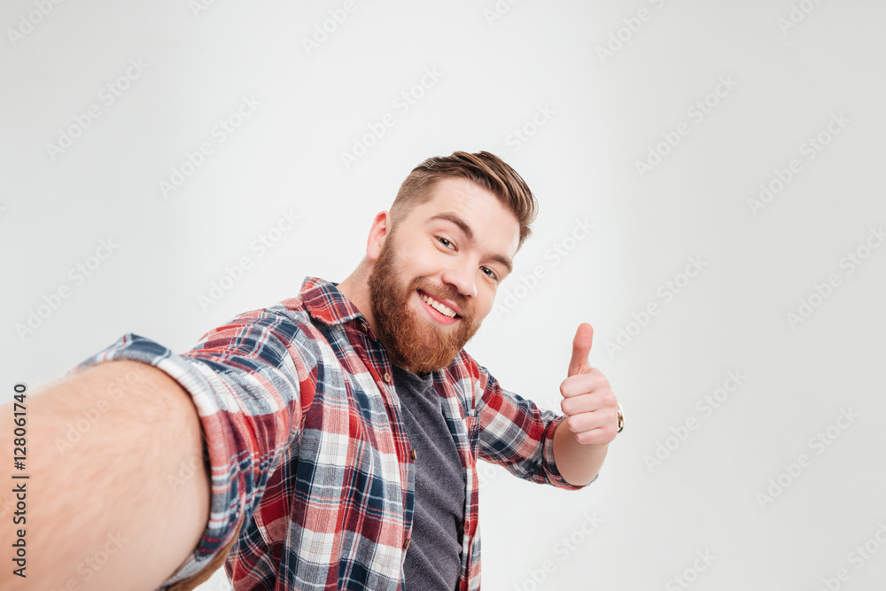 Happy casual man taking selfie and showing thumbs up gesture