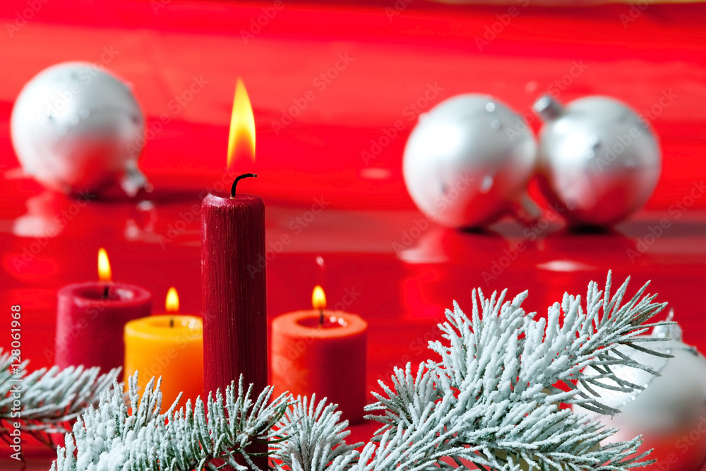 Flaming candles with Christmas twig on the red background