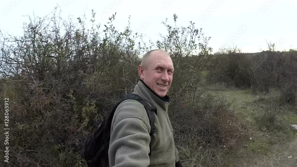 Happy man do selfie and walks outdoors on track among bushes Happy man do selfie and walks outdoors on track among bushes