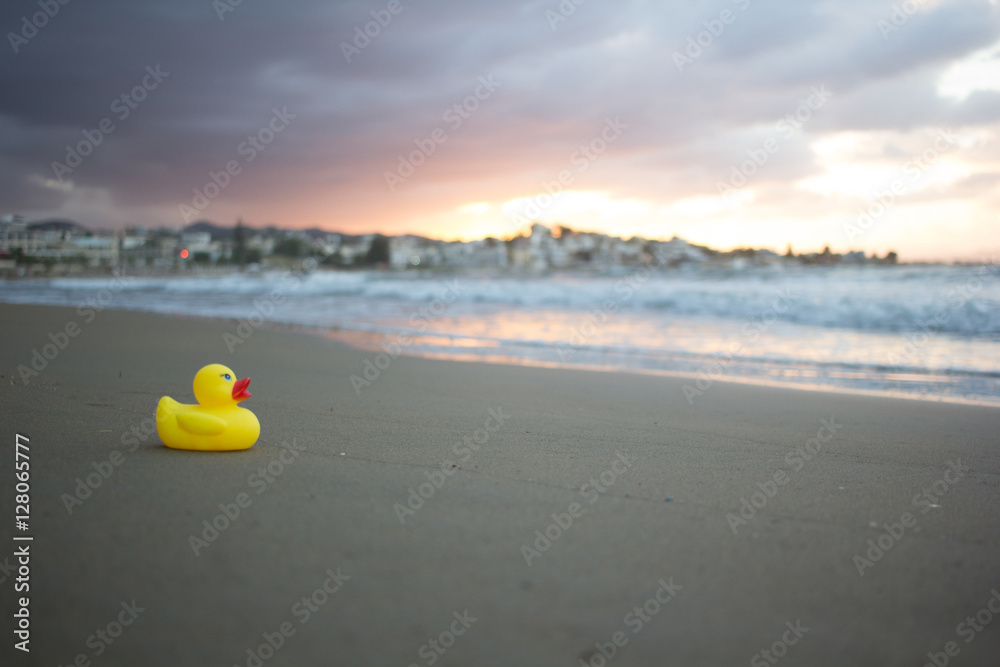 Yellow small toy duckling on sand beach in evening. Crete, Greece. Yellow small toy duckling on sand beach in evening. Crete, Greece.