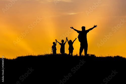 Silhouette father and children standing raised hands up on sunset happy time family concept