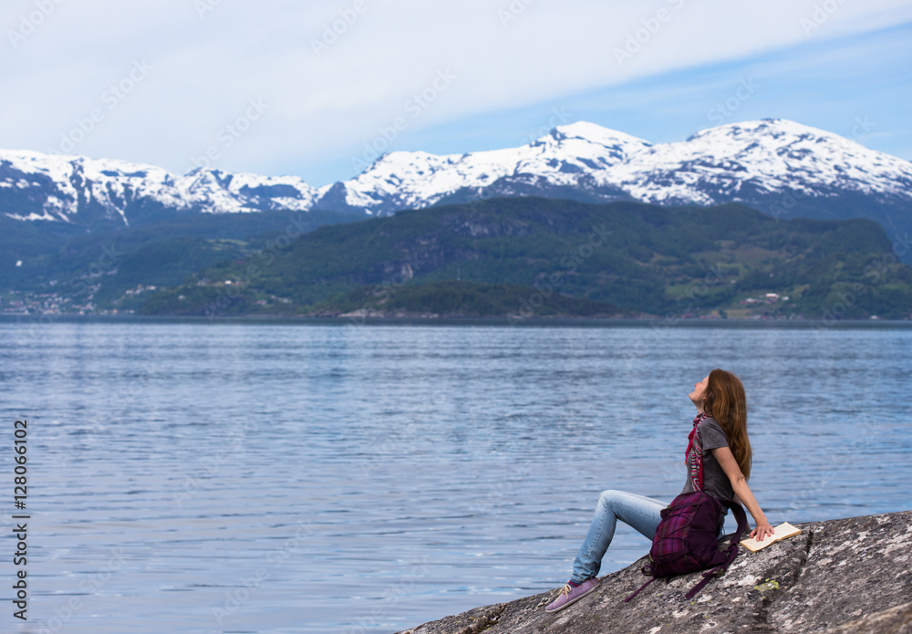 girl reading on a fjord coast