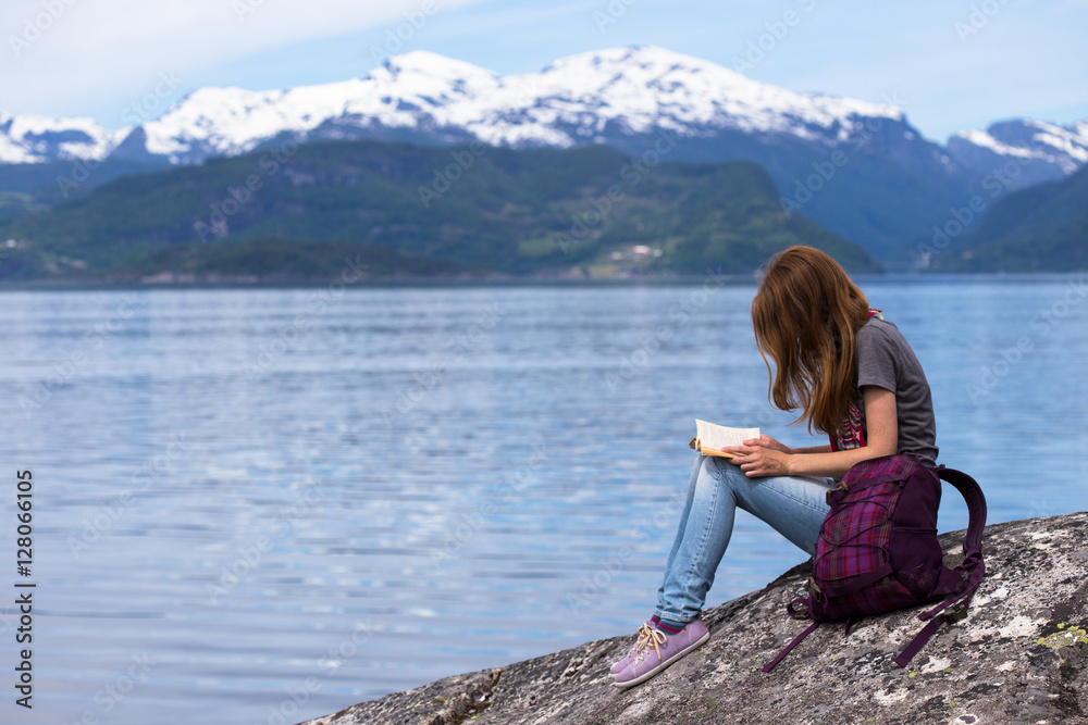 girl reading on a fjord coast