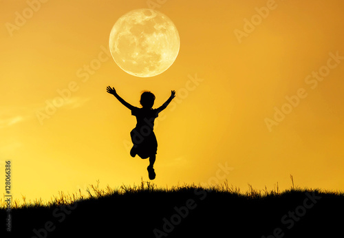 silhouette happy little girl  jumping to sky on sunset with full moon.