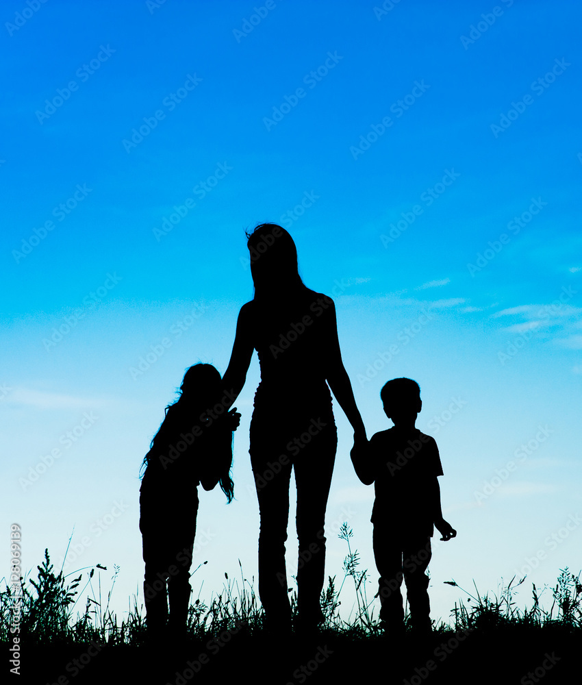 silhouette mother and children holding hands at sunset
