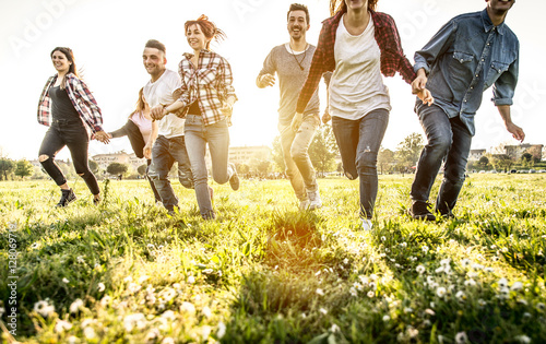 Group of friends running happily together in the grass