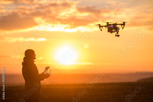 man playing with the drone. silhouette against the sunset sky photo