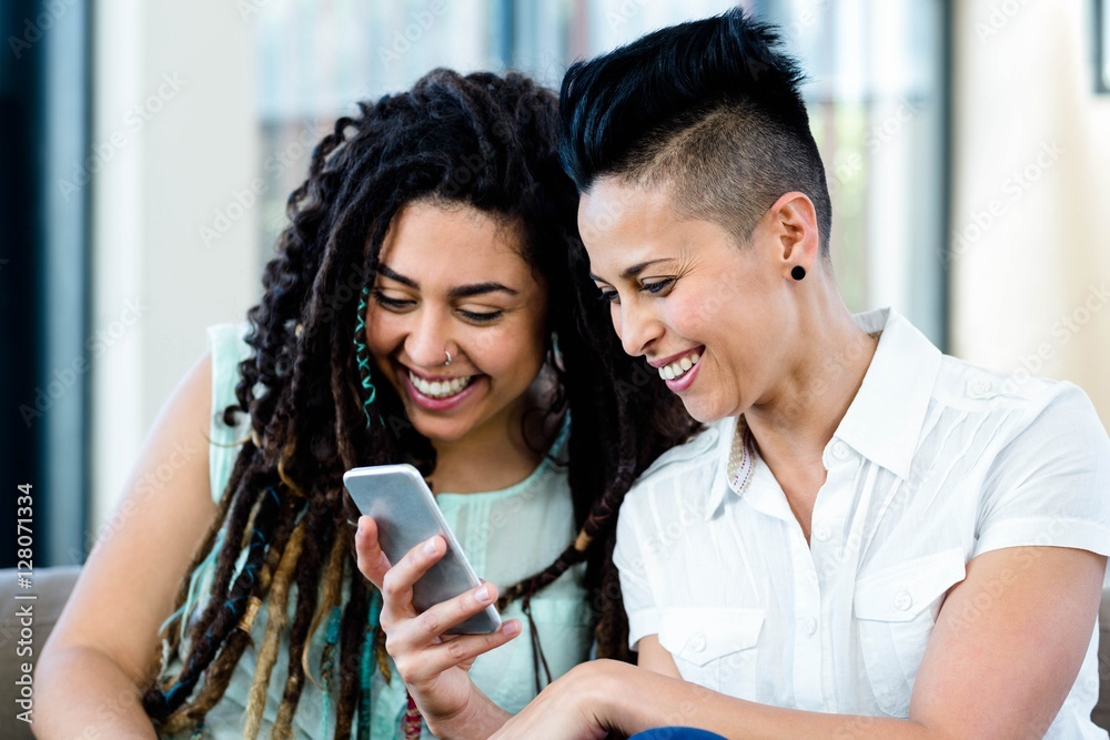 Lesbian couple looking at mobile phone and smiling