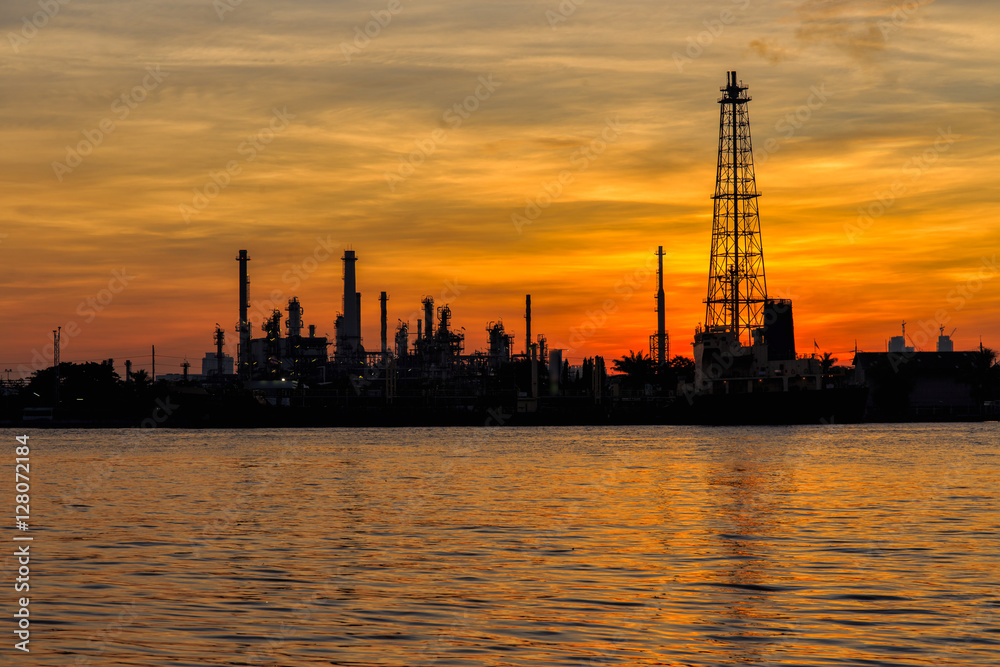 Oil refinery silhouette along the river at sunrise time