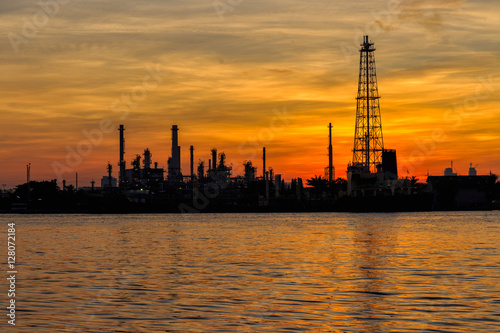 Oil refinery silhouette along the river at sunrise time