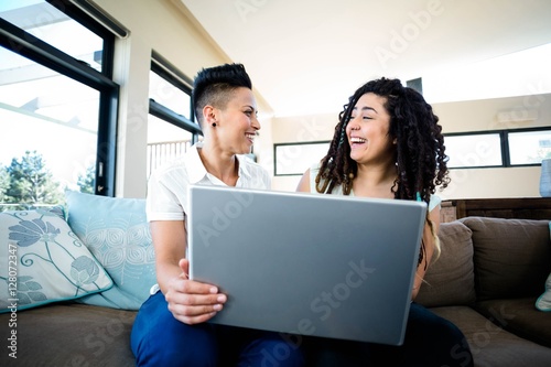 Lesbian couple smiling while using laptop