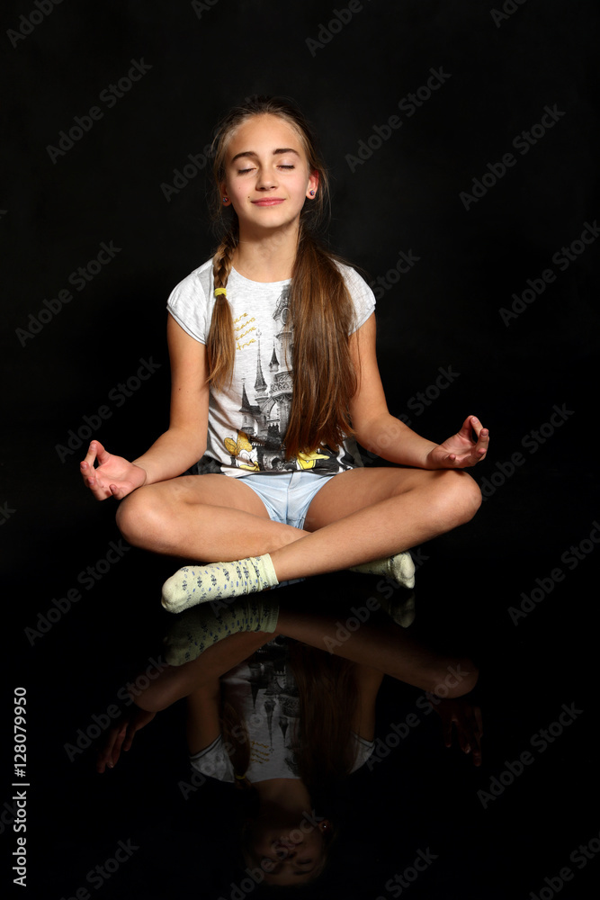 Śliczna dziewczynka medytuje, ćwiczy jogę, na czarnym tle. - obrazy, fototapety, plakaty 