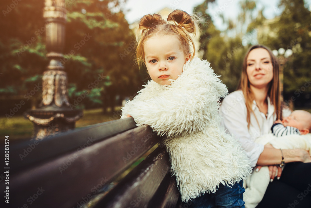 mother and two daughters rest on a bench