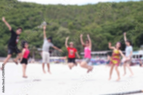 Group of people jumping at beach, blurred background. Happiness, success, friendship and community concepts.