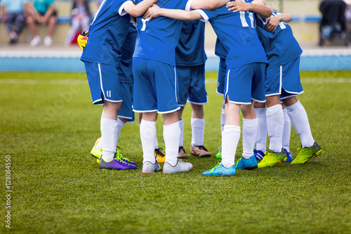 Young football soccer players in blue sportswear. Young sports team on pitch. Pep talk before the final match. Soccer school tournament. Children on sports field