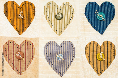 Old antique quilt with heart design and button centers. Warm tones with stripes in the squares of the quilt sampler.