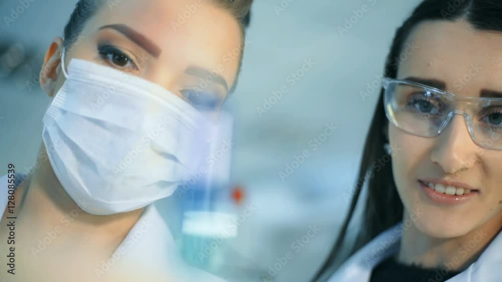 Two attractive female scientists studying test tube in laboratory Two attractive female scientists studying test tube in laboratory