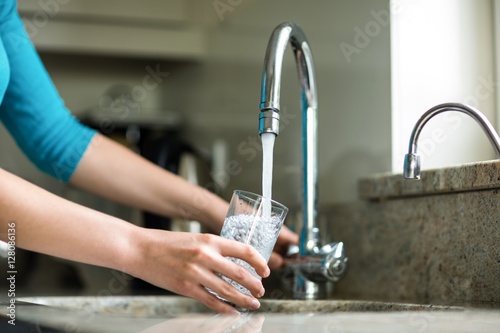 Pretty blonde woman filling a glass of water