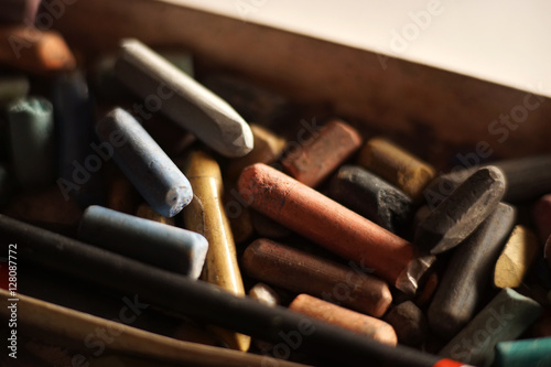 Pastel crayons piled in a box. Backlight.