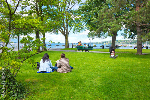 Geneva, Switzerland - The people sitting on the grass in a park the waterfront