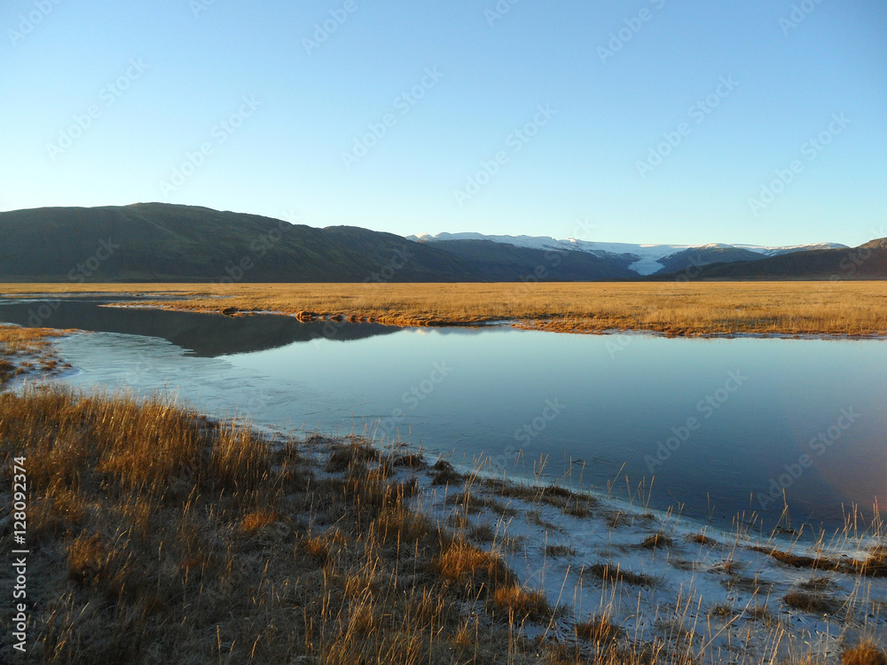 Reflection of mountain range and blue sky on a freezing lake, the southern part of Iceland 