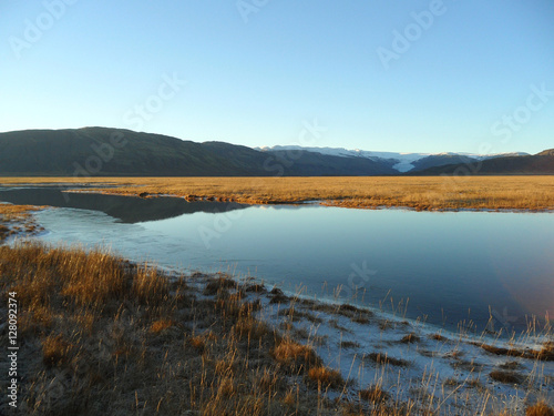 Reflection of mountain range and blue sky on a freezing lake  the southern part of Iceland 