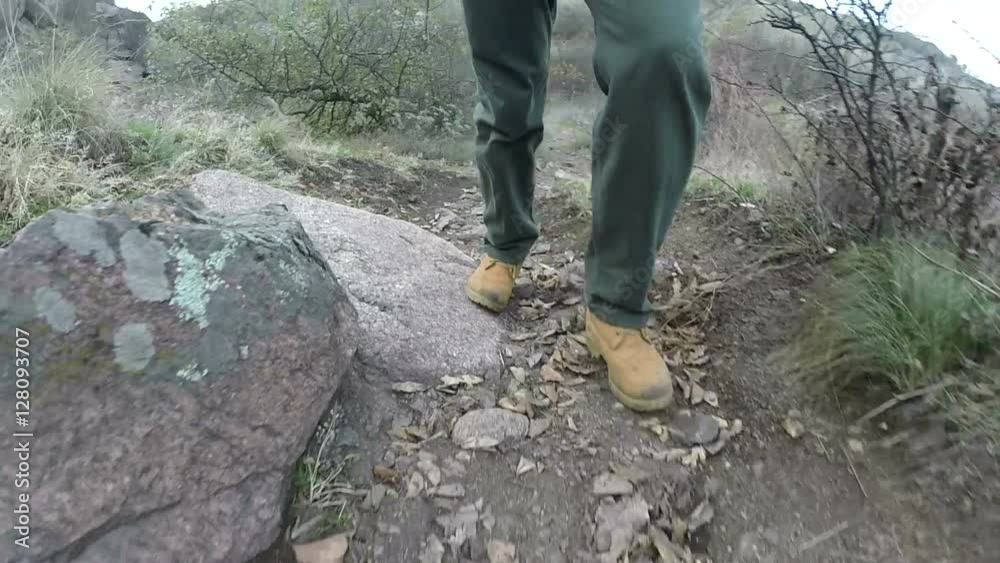 Male legs in yellow boots go on track in hill. Male legs in yellow boots go on track in hill.