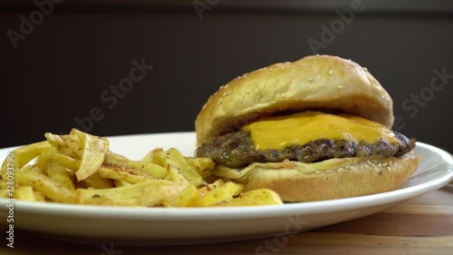 Melted Cheese burger with french fries. Rotating on plate