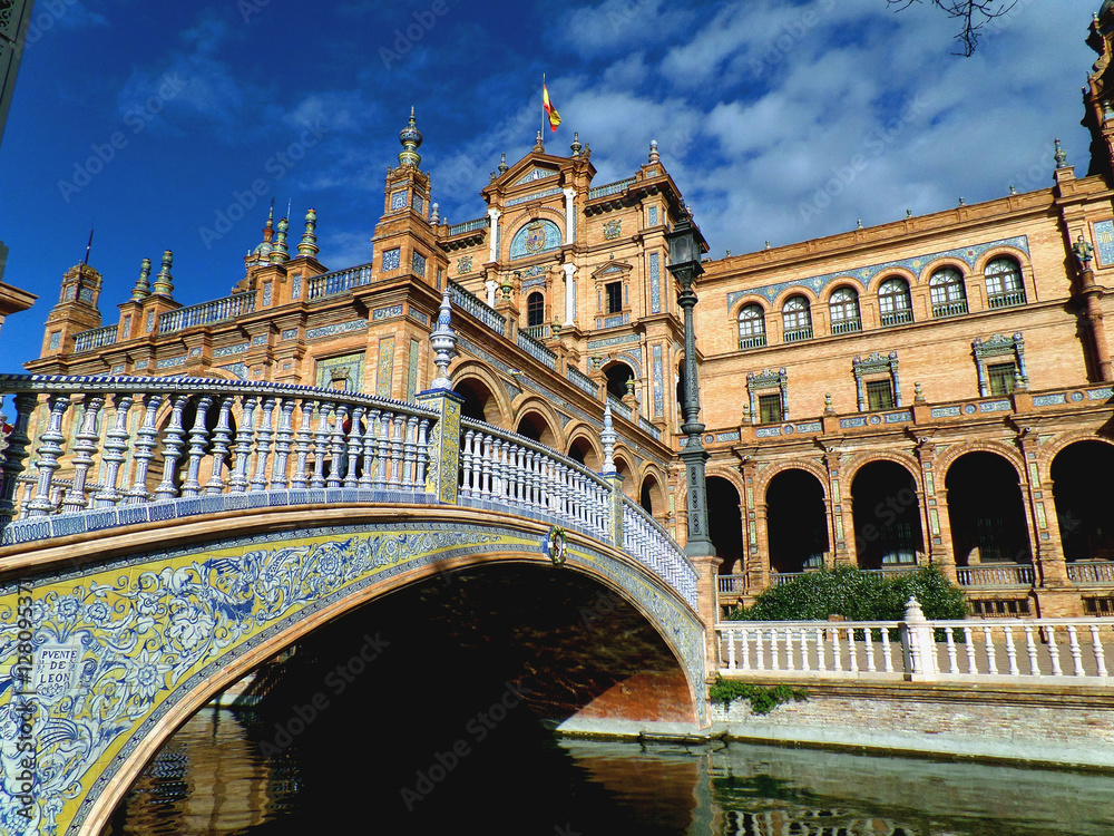 Gorgeous decorated bridge and stunning architecture against vivid blue sky at Plaza de Espana of Seville, Spain 