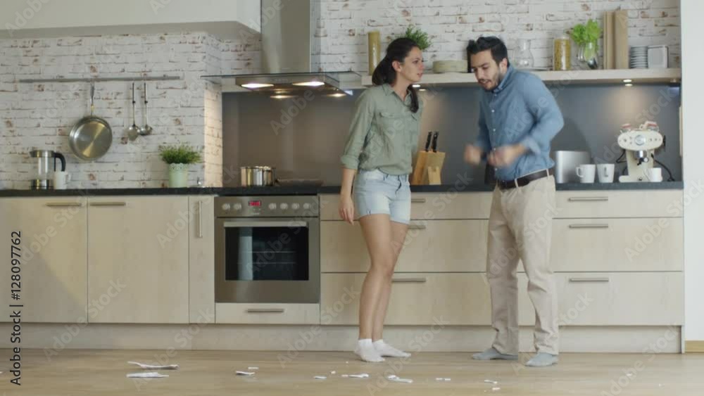 Young Couple Quarrels in the Kitchen. Girl Had Enough and She Breaks the Plate. Man Screams in Frustration and Angrily Gesticulates. Slow Motion. Shot on RED Cinema Camera in 4K (UHD). Young Couple Quarrels in the Kitchen. Girl Had Enough and She Breaks the Plate. Man Screams in Frustration and Angrily Gesticulates. Slow Motion. Shot on RED Cinema Camera in 4K (UHD).