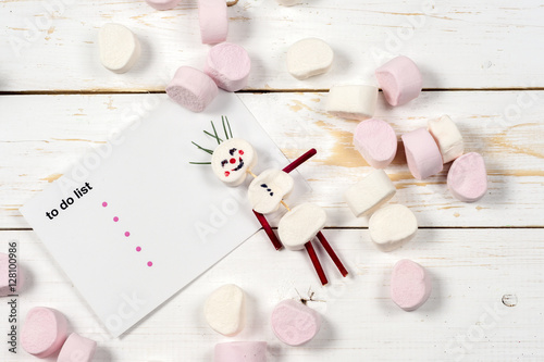 Christmas card with fun marshmallow snowman in green cup, tree