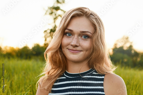 A close-up of a happy pretty girl with wrinkles and dimple on her face. A light-haired girl looking strairht in the camera on green background