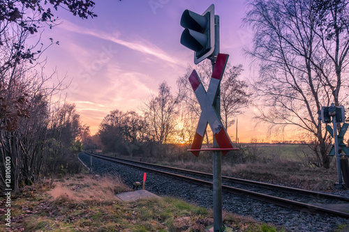 Andreaskreuz an den Schienen im Sonnenuntergang photo